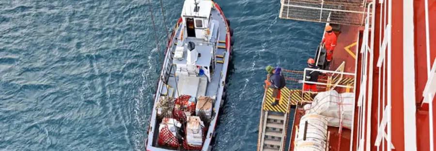 Supply boat alongside a merchant vessel during ship supply delivery